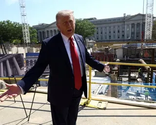 a man in a suit gestures in from of a building site