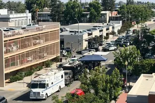 An aerial view of a Bakersfield street with police vehicles, an armored vehicle, and a canopy structure near a parking garage