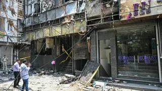 法医团队成员周三在印度首都新德里发生大火的酒店前拍照。（图取自法新社）