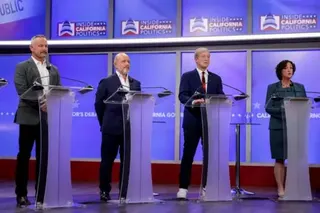 Getty Images There are four people stood behind podiums on a stage. The two figures in the centre are among the leaders in the polls. Steve Hilton is bald and bearded and wearing a dark suit and white shirt. To his left is Tom Steyer who is wearing a dark suit, red tie and white trainers.
