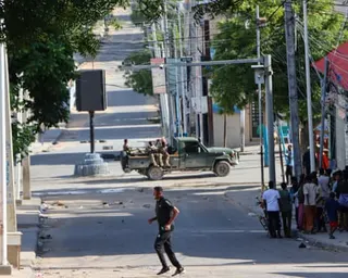 People watch as a pickup truck carrying men in the back with weapons drives along a road.