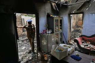 A Sri Lankan police officer inspects the charred elderly care home on Thursday. Photo: AP