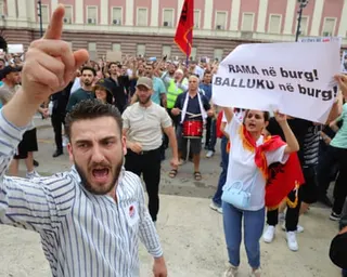 Protesters in Tirana hold up banners and shout in protest over the proposed development in Albania