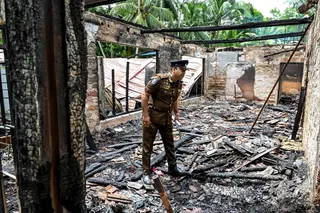 A police personnel inspects the burnt house on Thursday, a day after a fire broke out at an elder care home in Sri Lanka’s Batagoda. Photo: AFP