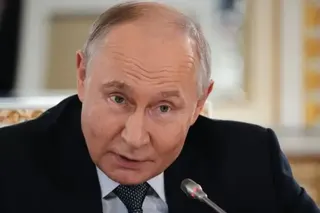 EPA Putin dressed in a dark blue suit, light blue shirt and spotted tie leans into a microphone, his eyebrows raised, at a press conference