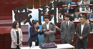 林珍羽把戰鬥陀螺交給蔣萬安，但蔣萬安沒拿好，讓陀螺掉到地上。（圖／中天新聞）