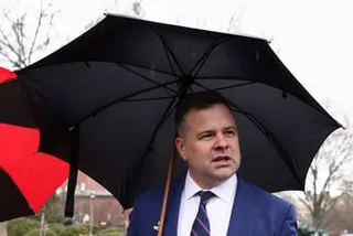 a man speaks while holding an umbrella