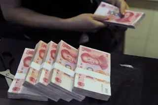 An employee counts Chinese 100 yuan banknotes at a branch of China Merchants Bank in Hefei, Anhui province. Photo: Reuters