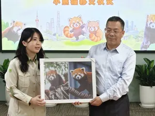 上海動物園5日舉行小貓熊移交儀式，由上海市動物園園長裴恩樂（右）將象徵兩隻小貓熊...