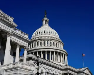 White stone dome of the US Capitol against a blue sky.