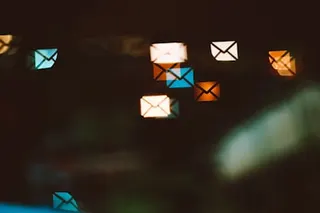a series of illustrated and illuminated email symbols, in different colors, on a darkened background.