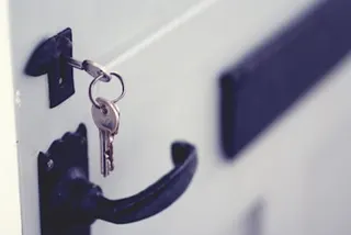a photo of a set of keys left in a door lock, a visualization of a security vulnerability.
