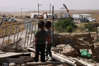 Children watch as new prefabricated Jewish homes are secured into placed along a road that leads toward the Palestinian village of Umm al-Khair on May 20. Photo: AFP