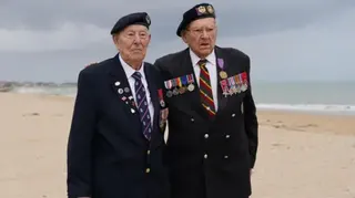 Ken Hay (R) stands next to Henry Rice (L) on a cloudy beach in France. They both wear jackets with a number of medals