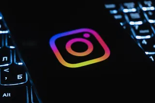 a photo of Instagram's logo on a phone on a darkened background featuring a lit-up keyboard