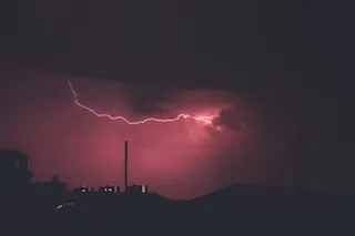 a photo showing red lightning in the darkened sky, with cell tower and networking equipment in the background.