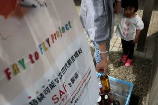 A woman brings used cooking oil to a waste oil collection point for Japan’s “Fry to Fly” project in Adachi ward, Tokyo, on April 18. Photo: Reuters