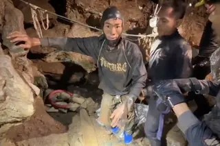 Rescuers pull out a trapped person from a flooded cave.