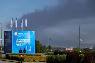 FILE PHOTO: Police officers stand in front of a banner and flags with the logo of the St. Petersburg International Economic Forum (SPIEF) as heavy smoke billows in the background after Ukrainian drones hit infrastructure, according to governor Alexander Beglov, in St Petersburg, Russia June 3, 2026. REUTERS/Stringer/File Photo