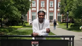Eduardo Camavinga leans on a sign on the site of the Harvard Business School