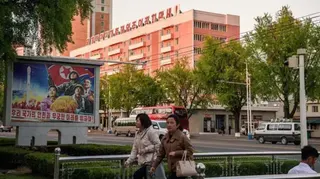 AFP via Getty Images Pedestrians walk past a mural (L) that reads "For the safety and endless future of our nation", as a building adorned with the slogan "Long live the great people-first politics" is seen in the background in Pyongyang on May 8, 2026.