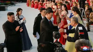 中國領導人習近平訪問朝鮮時與人群中的一人握手，朝鮮領導人金正恩與妻子李雪主到場迎接。