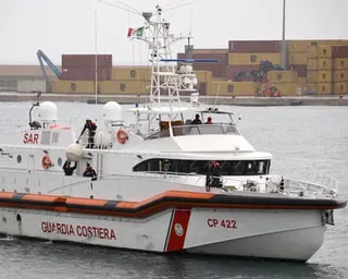 An Italian Coast Guard vessel marked CP 422 with crew members on deck and orange inflatable pontoons