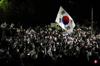 韩国大批示威者星期六（6月6日）聚集在首尔地方选举计票地点，继续抗议部分选区选票短缺问题。抗议人群挥舞巨大的韩国国旗，高呼“重新选举“。 （路透社）