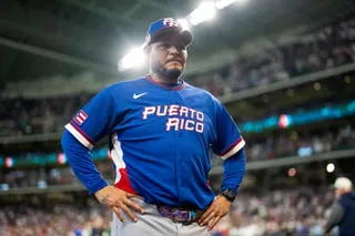 a man in a baseball uniform stands with his hands on his hips