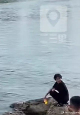 蹲在岸邊淡定看著14歲少女溺水的黑衣男性，被拍到回頭疑似冷笑。（取材自二三里資訊...