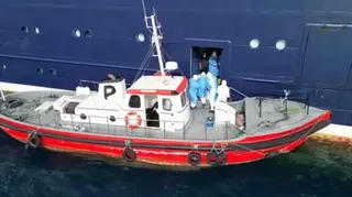 Passenger being evacuated from cruise ship onto a smaller boat.