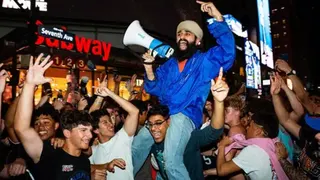 Getty Images Crowds of fans cheering and celebrating, with one fan sitting on another's shoulders and yelling into a megaphone