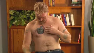 Graham Platner pointing to a covered tattoo on his arm during an interview in Portland, Maine