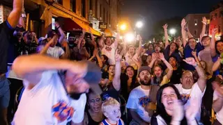 Corbis via Getty Images Dozens of fans cheering and watching a basketball game in the street
