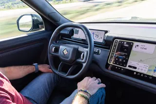 A man sits at the wheel of a Rivian R2
