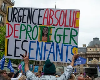 A crowd outside the justice ministry in Paris holds placards. One reads, in French, 'absolute urgency to protect the children', and has a small picture of the murdered girl.