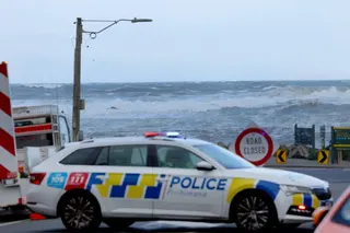 A police car is seen parked across a closed road as stormy seas pound the coastline of Owhiro Bay, a suburb of New Zealand’s capital Wellington, on Tuesday. Photo: AFP