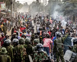 Chaotic scene of demonstrators confronting police who are wearing military-style uniforms