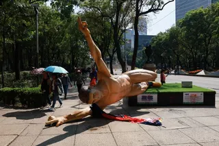 People walk near the fallen statue of a soccer player