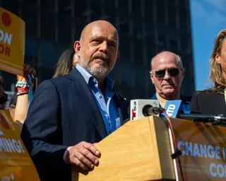 a man speaks into microphone while surrounded by people