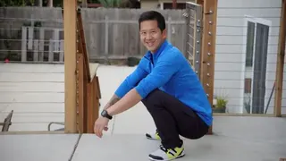 一名穿著藍色上衣的人示範深蹲姿勢，雙腳平放地面，雙手放在膝蓋上