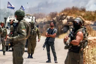 An Israeli settler (C) stands between Israeli security forces gathering before Palestinians along a road who had gathered to protest Israeli settlers reportedly setting fire to an area in the Palestinian village of Idna, west of Hebron in the occupied West Bank, on June 5, 2026.