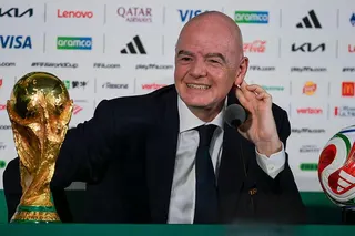 FIFA president Gianni Infantino, in dark suit and tie and white shirt, speaks next to the World Cup trophy and a football during a news conference on the eve of the opening match of the 2026 World Cup