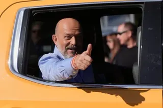 A man giving a thumbs-up sign from a car.