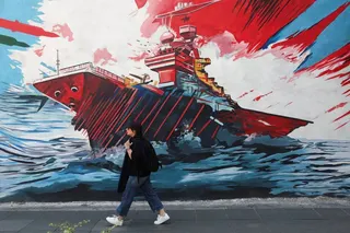An Iranian woman walks next to an anti-US mural on a street in Tehran on Wednesday. Photo: West Asia News Agency via Reuters