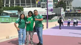 Will Grant / BBC Javier Pérez and his family, wearing Mexico jerseys as they stand in front of the Azteca stadium and give the thumbs up to the camera.