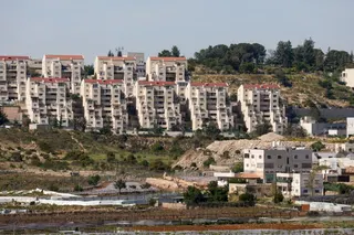 The Kiryat Arba settlement appears in the background near Palestinian houses adjacent to road 60, near Hebron, in the Israeli-occupied West Bank