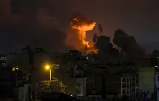 A large plume of smoke and fire rises over Tehran at night