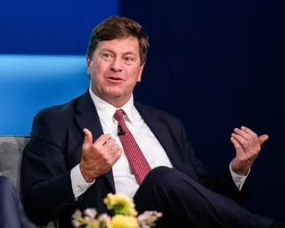 a man in a suit speaks while seated on stage