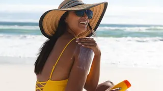 Woman applying sunscreen to her face outdoors.
